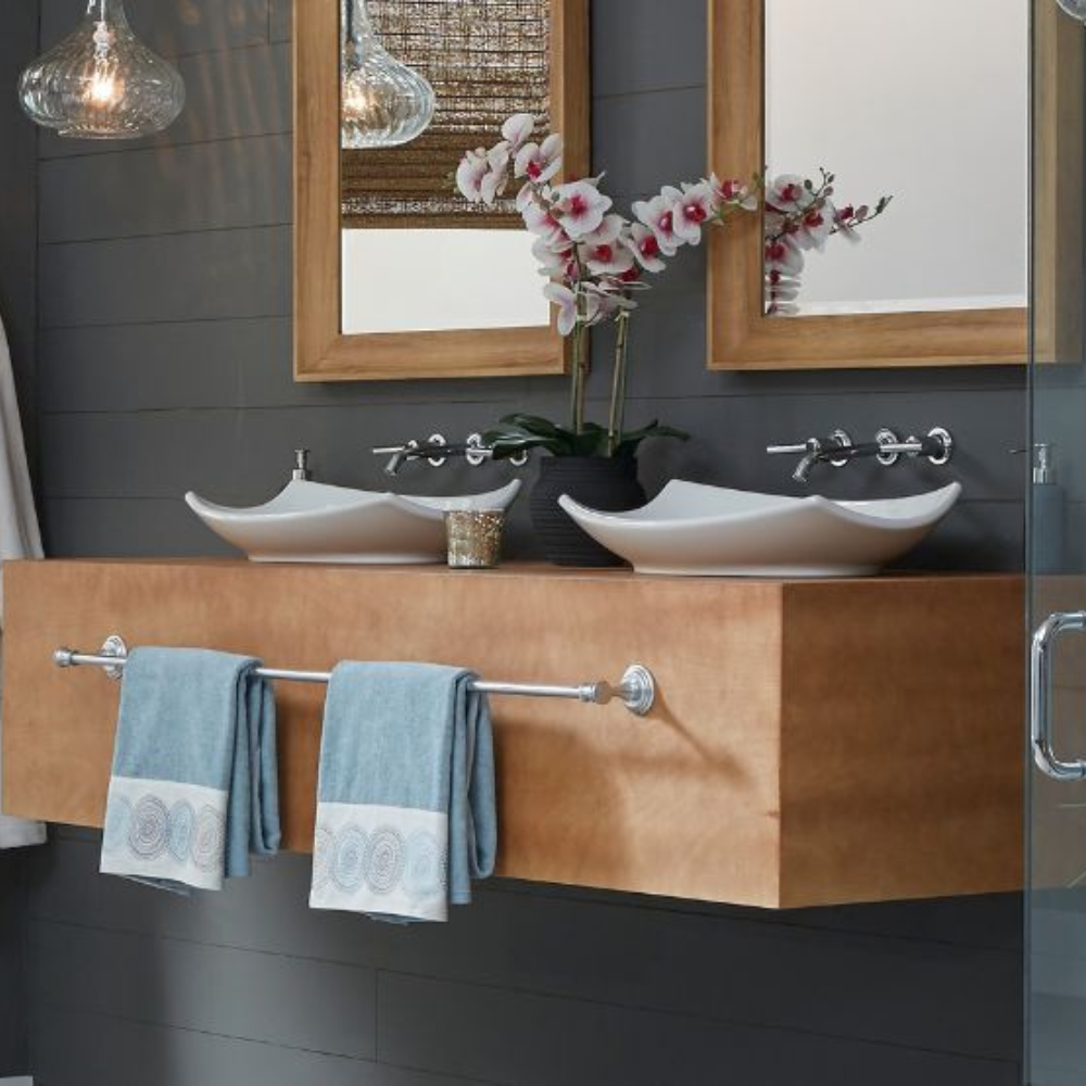Double floating wooden vanity with wave-shaped white vessel sinks and wall-mounted chrome faucets.